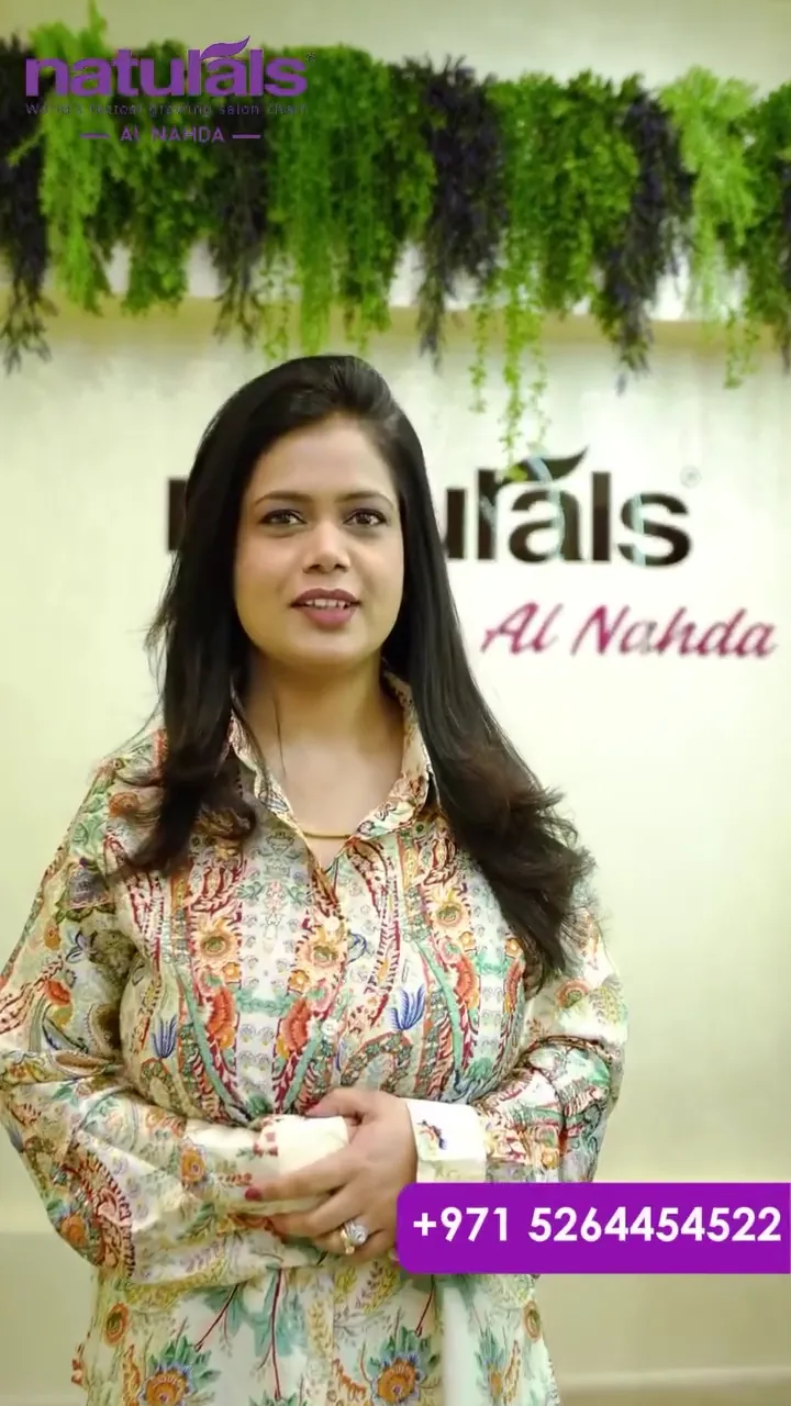 A Naturals team member in front of the Al Nahda salon sign